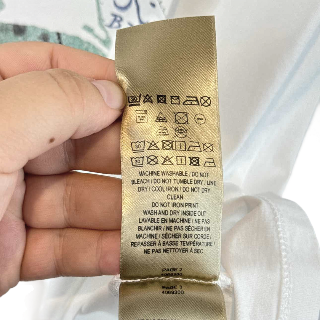 a person is holding a gold label on a white shirt